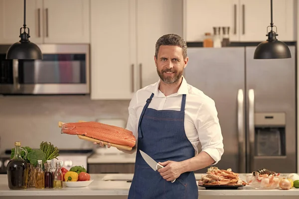 stock image positive man cook delicacy salmon fish. man cook delicacy salmon in the kitchen. photo of man cook delicacy salmon. man cook delicacy salmon.