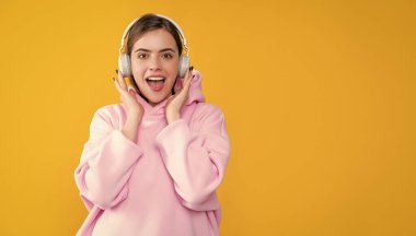 Mutlu kız sarı arka planda kulaklıkla müzik dinliyor..