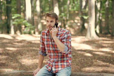 Kareli tişörtlü genç yakışıklı telefonda konuşuyor..