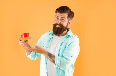 Mutlu sakallı adam sarı arka planda sabah kahvesini sunar..