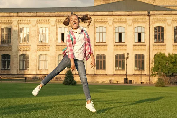 Happy active teen girl jumping in school yard outdoors, schooling.