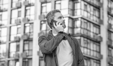 Adamın cep telefonundaki görüntüsü. Adamın dışarıda cep telefonu var. Sokakta cep telefonuyla konuşan bir adam. Adam cep telefonundan arıyor..