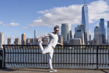 Sporcu kaslarını esnetiyor ve antrenmana hazırlanıyor. Açık havada sporcunun esneme hareketleri. Sporcu koşudan sonra kaslarını esnetiyor. Sporcu esnekliği artırmak için esniyor. Statik germe.