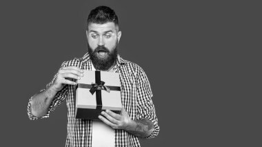 Gri arka planda hediye kutusu olan olgun sakallı adam..