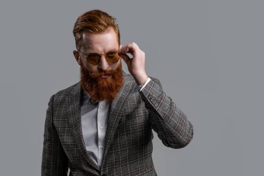 Formalite içinde smokin giyen kızıl saçlı adam. Erkekler şık erkek kıyafetleri giyer. Resmi takım elbiseli sakallı beyefendinin zarafeti. Resmi kıyafet. Formalite icabı smokinli adam gride tek başına. Uzayı kopyala Cilalanmış zarafet.