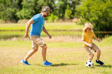 Baba ve oğul birlikte dışarıda eğleniyorlar. Baba ve oğul arasındaki açık hava maceraları. Aktif baba oğul yaz tatili için futbol oynuyor. Baba ve çocuk dışarıda takım oluşturuyorlar..