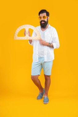 Stüdyoda tam boy geometri açıölçer var. Adam arka planda geometri açıölçer tutuyor. İnsan tutuşu geometri iletkeninin fotoğrafı. Man hold geometri açıölçer sarı üzerine izole.