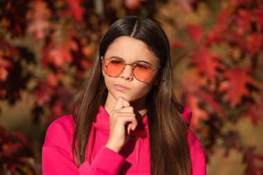 Gençlik modelinin sonbahar havası açık havada kafa yoruyor. Dışarıdaki parkta sonbahar yaprakları. Kız portresi. Sonbahar kızı güneş gözlüğü takıyor ve şık görünüyor. Sonbahar sezonu. Kız sonbaharda rüya görür.