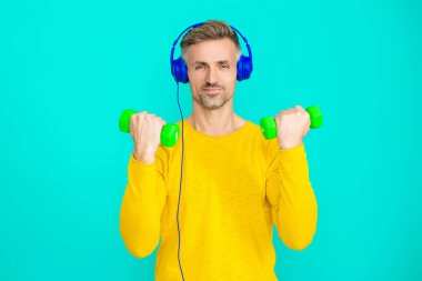 Halterli ve dambılı bir sporcu. Müzikli spor salonu. Spor salonu. Egzersiz müziği. Güçlü sporcu adam seni. Olgun bir adam mavi üzerine izole edilmiş spor eğitimi yapar. Kişisel sporlar.