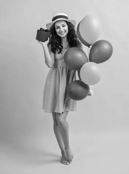 photo of smiling birthday woman with gift balloons. birthday woman with gift balloons isolated on yellow. birthday woman with gift balloons in studio. birthday woman with gift balloons on background.