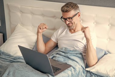 Gözlüklü olgun bir adamın laptopla yatakta çalışmasına sevindim..