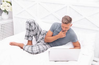 Düşünen adam evde yatakta serbest çalışıyor. Adam evde, yatak odasında serbest çalışıyor. Evde dizüstü bilgisayarlı serbest çalışan bir adamın fotoğrafı. Adam evde serbest çalışıyor..