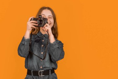 Mutlu çocuk fotoğrafçı sarı arkaplanı çekerken kameraya bakıyor, boşluğu kopyala.