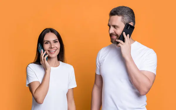 Smiling couple talking on mobile phones. Happy man and woman making mobile call studio. Mobile phone conversation. Mobile communication.