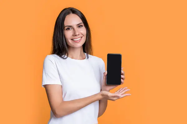 Woman smiling presenting mobile device. Mobile technology. Mobile communication. Presenting product, copy space. Happy woman presenting mobile phone.