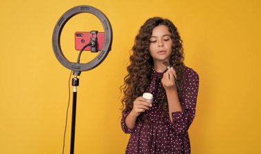 Uzun kıvırcık saçlı genç çocuk blogda pudra fırçası için video çekiyor.