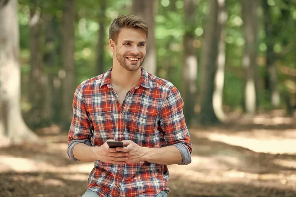 young handsome man in checkered shirt texting on phone outdoor.