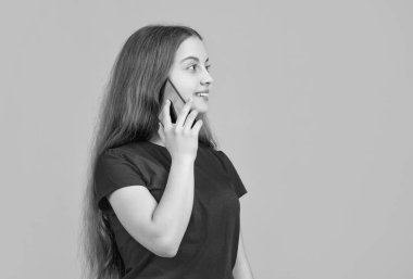 Çocuk sarı arka planda akıllı telefondan konuşuyor..