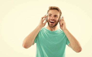 Müzik dinleyen heyecanlı bir adam beyaz stüdyoya kapalı bir şekilde bakıyor. Müzik için kulaklık takan kaygısız bir adam. Meloman müzik dinlemekten zevk alıyor, boşluğu kopyala.