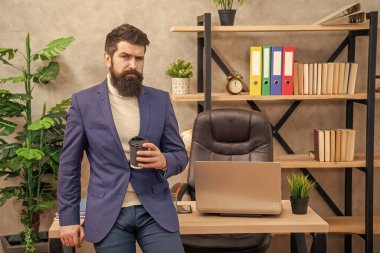 Takım elbiseli, çay ya da kahve içen, ofis masasında oturan ciddi bir yönetici..