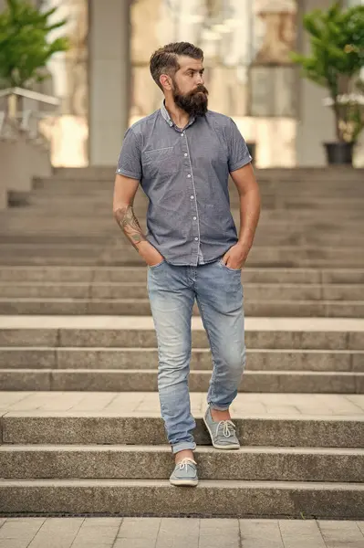 bearded hipster walk downstairs. full length of hipster with beard. hipster man outdoor.