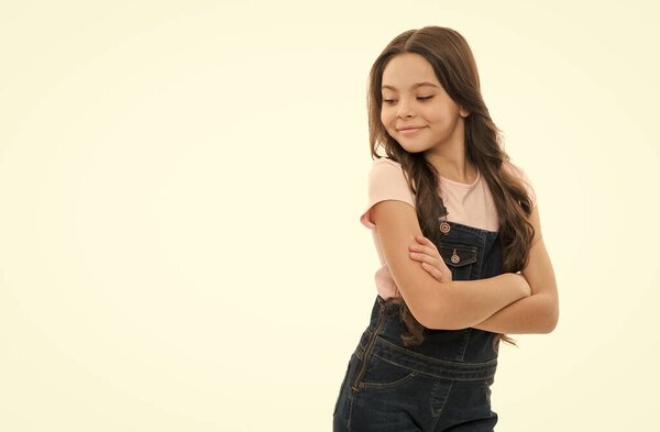Happy teenager smiling in trendy teen wear studio. Teen girl keeping arms crossed isolated on white. Teen model in casual fashion style, copy space.