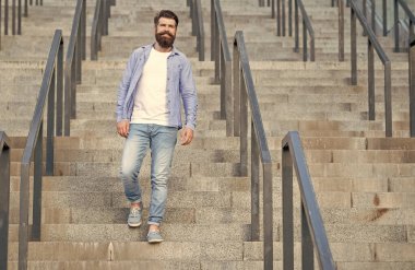 Sakallı adam aşağı iniyor. Sakallı bir adam. Merdivenlerde hippi bir adam var..