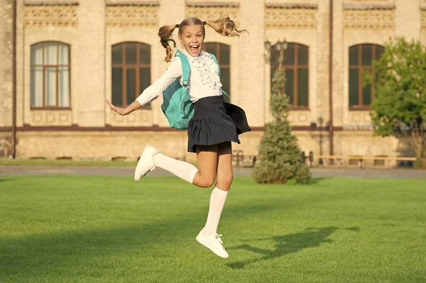 Excited schoolgirl jumping midair, school. Energetic teenage girl carrying school bag. Back to school.