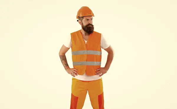 sad builder man in uniform. bearded builder in orange vest. studio shot of builder wearing helmet. builder isolated on white background.