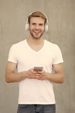 Mutlu adam mp3 müzik listesinin kulaklıkla fotoğrafı. Adam mp3 müzik listesini açıyor. Adam dışarıda mp3 müzik listesi kullanıyor. Beyaz gömlek giyen bir adam mp3 müzik listesini seçer.