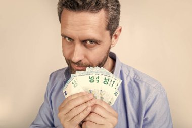 Adam para kazanarak gülümsüyor. Para kazanan bir adamın fotoğrafı. Stüdyo geçmişine izole edilmiş para kazanan bir adam. Stüdyoda para kazanan bir adam..