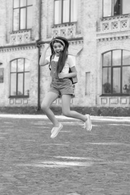 cheerful denim girl with backpack jumping outdoor.