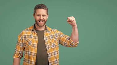 Stüdyoda güçlü, olgun bir adam. Olgun adam kareli gömlek giyer. Sakallı, olgun bir adamın fotoğrafı. Yetişkin adam mavi arka planda izole.