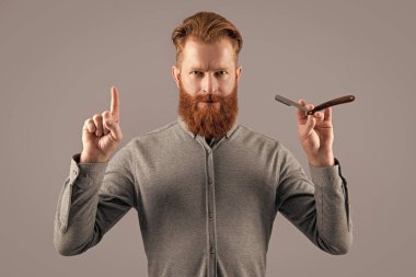 Berber stüdyosundaki fikir adamından esinlendim. Adam tıraş olmak için berber bıçağını tutuyor. Gri arka planda berber bıçağıyla tıraş olan bir adam. Berber adam bıçakla tıraş oluyor..