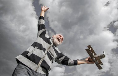 Gökyüzü geçmişinde yaşlı bir adam. Emeklilikteki son sınıf. Dışarıda oyuncak uçağı olan yaşlı emekli bir adam..