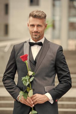 Özel bir durum için. Özel durumlar için gül taşıyan neşeli bir adam. Smokinli adam özel bir gün için dışarı çıktı..