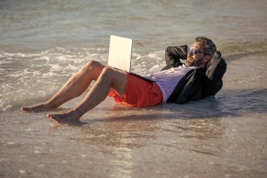 Yazın dizüstü bilgisayarı olan takım elbiseli bir iş adamı. İş adamı yazın denizde iş yapmayı hayal eder. Yaz işi. Kumsalda dinlenen bir iş adamı. Uzaktan kumanda çalışıyor. İş adamı plajda rahatlar.