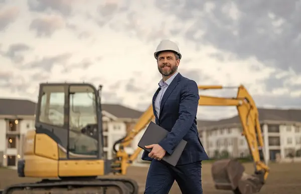 businessman with building plan, advertisement. businessman check building plan at site. businessman checking building plan outdoor. photo of businessman with building plan wearing hardhat.