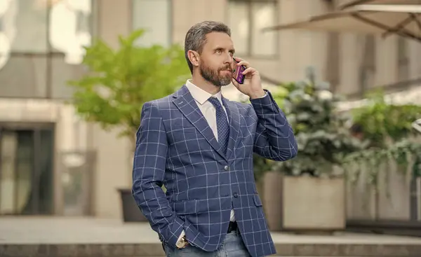 photo view of businessman call on phone and talk. businessman has phone call outdoor. businessman having phone call in the street. businessman call on phone outside.