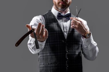 selective focus of barber man show blade in studio. photo of barber man. barber man isolated on grey background. barber man with scissors and blade.