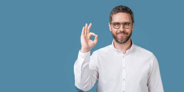 Gözlük şovuna bak. Mavi arka planda izole edilmiş. Olgun bir adam stüdyoda gözlük giyer. Gözlüklü adam. Olgun bir adamın fotoğrafı. Göz giysisine bak..