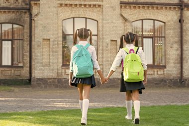 Okul çantalı iki kızın arka planı. Açık havada birlikte yürüyorlar..