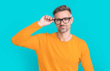 smiling man look in eyewear at studio. man look in eyewear on background. photo of man look in eyewear. man look in eyewear isolated on blue.