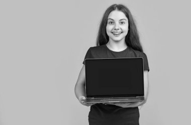 Sarı arka planda dizüstü bilgisayarı olan gülümseyen çocuk.