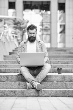 Dizüstü bilgisayarda yazıp merdivenlerde oturan ciddi bir serbest yazar. Serbest çalışan adam uzaktan kumanda için dizüstü bilgisayar kullanıyor. İnternette çalışan serbest çalışan adam. Çevrimiçi Serbest Çalışan.