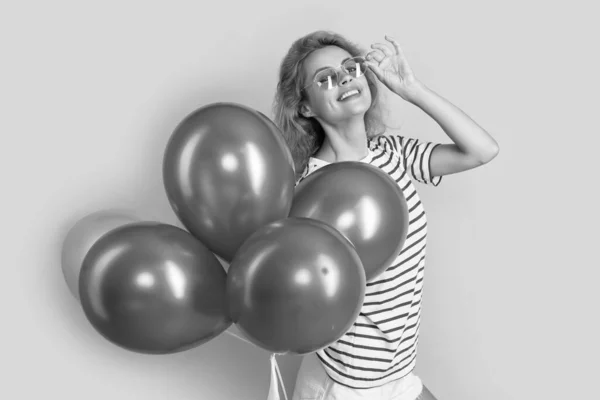 party girl with balloon in sunglasses. cheerful girl hold party balloons in studio. girl with balloon for party isolated on yellow background.