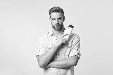 Stüdyonun arka planında tıraş losyonu var. Traş losyonu losyonunun fotoğrafı. Adam tıraş losyonunu elinde tutuyor. Adam traş losyonunu sarı renkte tutuyor..