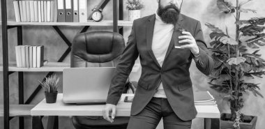 Profesyonel bir adam çay ya da kahve içerken, ofis masasında oturur, mola verir..