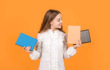 Genç kız ödevlerini defterle yapıyor. Çalışma kitabıyla çalış. Neşeli çocuk kitabı sunuyor. Okula dönüyorum. Çocukluk eğitimi. Bilgi günü. Çocuk defteri tut. Lise öğrencisi..