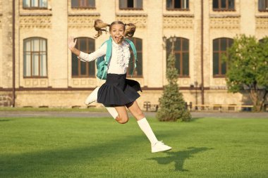 Havada zıplayan okul üniformalı heyecanlı genç kız. Enerjik liseli kız okula geri döndü. Okulda eğitim.